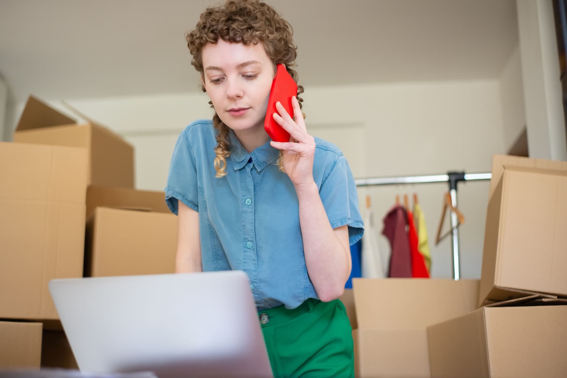 A tenant on the phone at home among moving boxes, asking a quick question